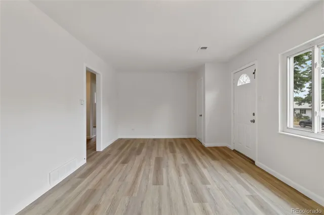 an empty room with wooden floor and windows