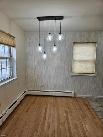 an empty room with wooden floor mirror and windows