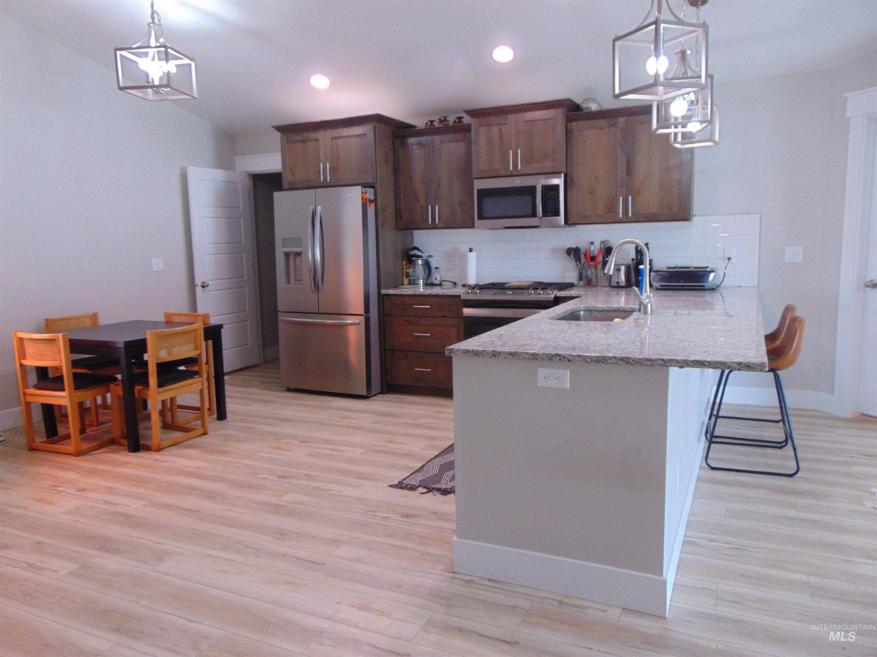 901 Campbell Street Vale, OR 97918 - Photo 7 of 22 Kitchen featuring a breakfast bar, stainless steel appliances, hanging lights, a peninsula, and light stone counters