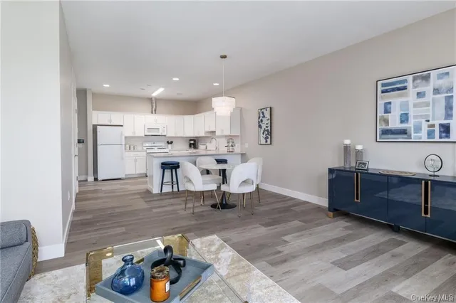 a living room with stainless steel appliances kitchen island granite countertop furniture and a wooden floor