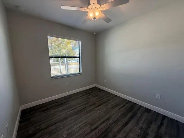 a view of an empty room with window and wooden floor