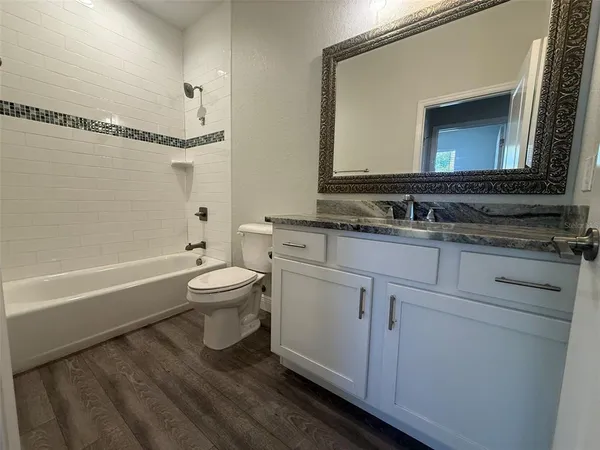 a bathroom with a toilet a sink a tub and mirror