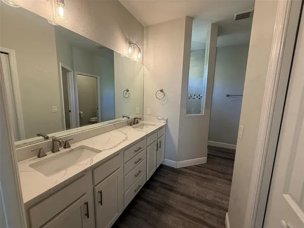 a bathroom with a double vanity sink and mirror with shower