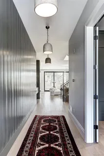 a hallway with white walls stairs and a rug