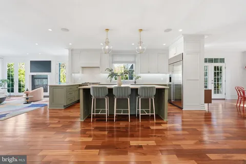 a kitchen with stainless steel appliances granite countertop a stove top oven a sink dishwasher a dining table and chairs with wooden floor