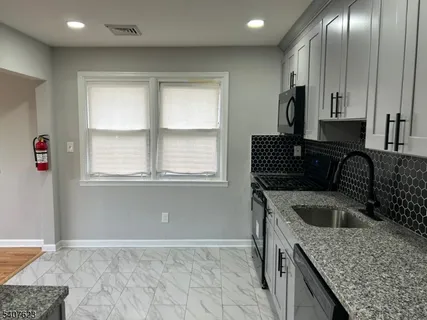 a kitchen with granite countertop a sink a stove and cabinets