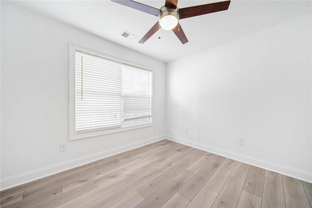 2140 Wildcat Cliffs Way Lawrenceville, GA 30043 - Photo 22 of 32 an empty room with wooden floor ceiling fan and windows