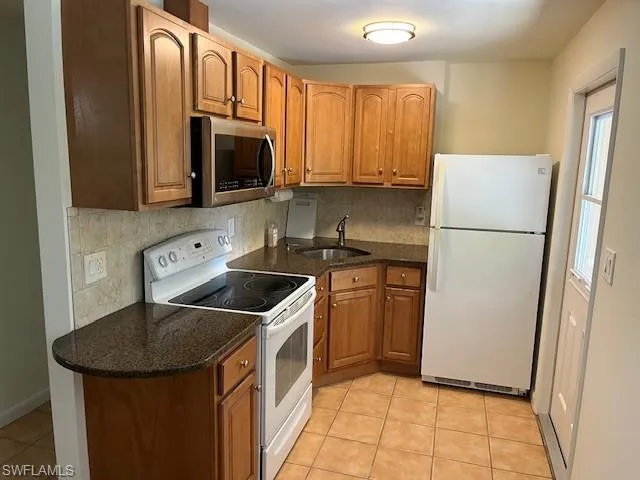 a kitchen with stainless steel appliances granite countertop a refrigerator a stove a sink and a microwave