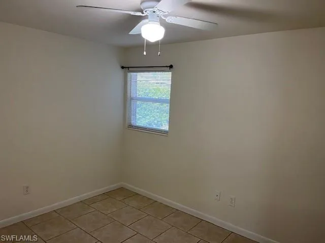 an empty room with a chandelier fan and windows