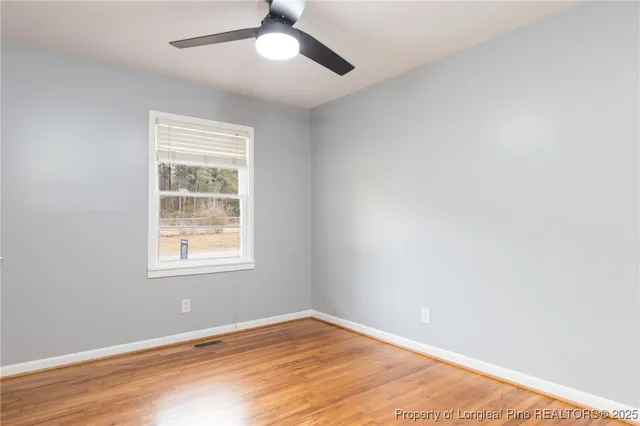 an empty room with a window and ceiling fan