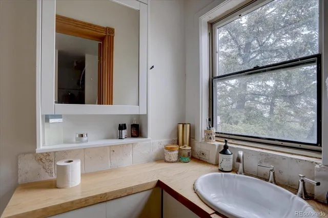 a bathroom with a granite countertop sink vanity mirror and a large window