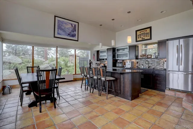 a kitchen with stainless steel appliances granite countertop a stove a refrigerator a kitchen island a table and chairs