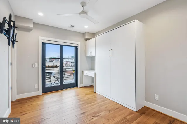 an empty room with wooden floor closet and windows