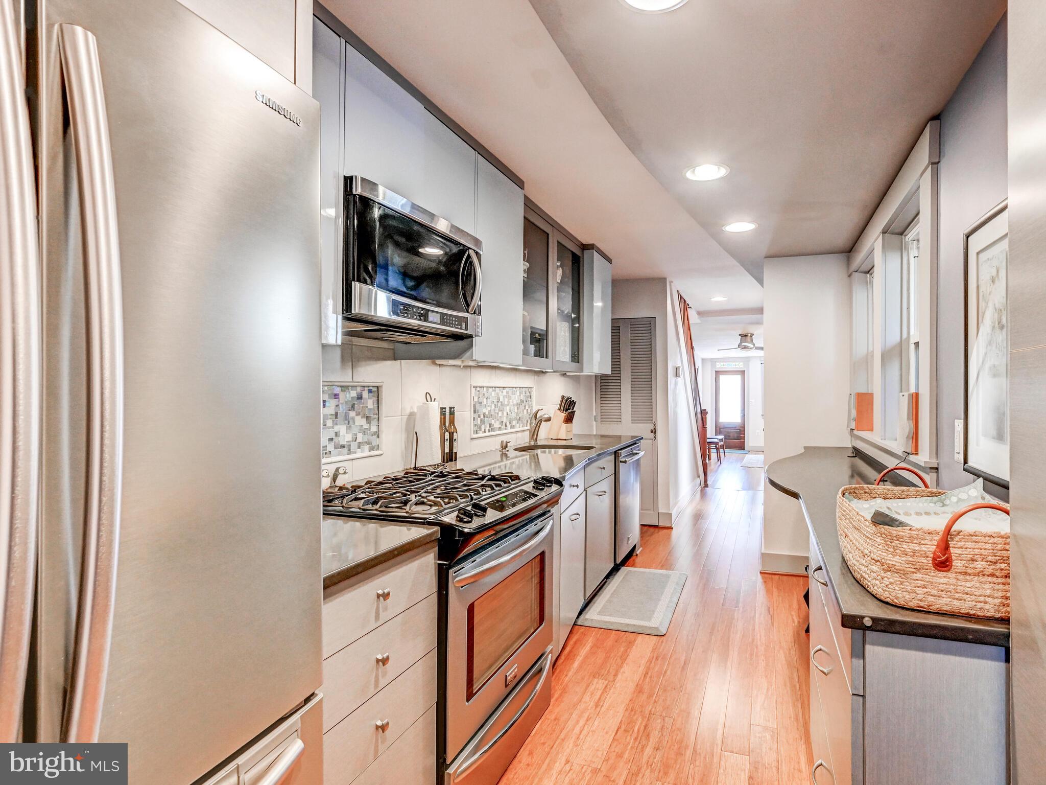 325 South Castle Street Baltimore, MD 21231 - Photo 8 of 31 a kitchen with stainless steel appliances granite countertop a stove top oven a sink dishwasher a dining table and chairs with wooden floor