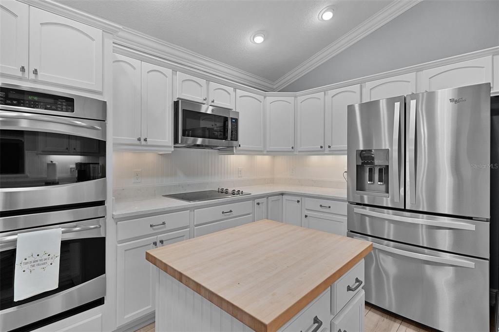 2211 Bachman Path The Villages, FL 32162 - Photo 13 of 60 a kitchen with white cabinets and stainless steel appliances