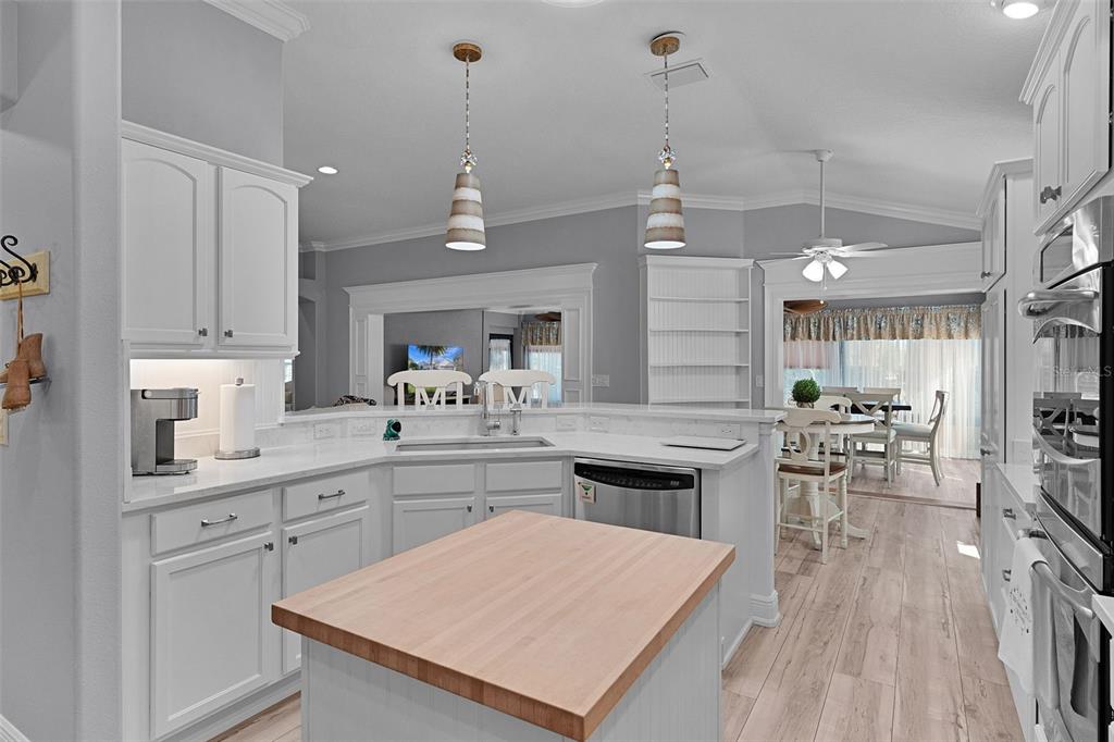 2211 Bachman Path The Villages, FL 32162 - Photo 14 of 60 a open kitchen with kitchen island a sink stove a dining table and chairs with wooden floor