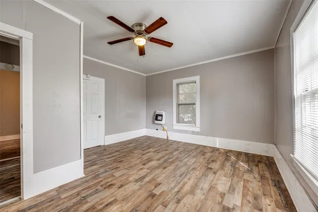 a view of empty room with wooden floor and fan