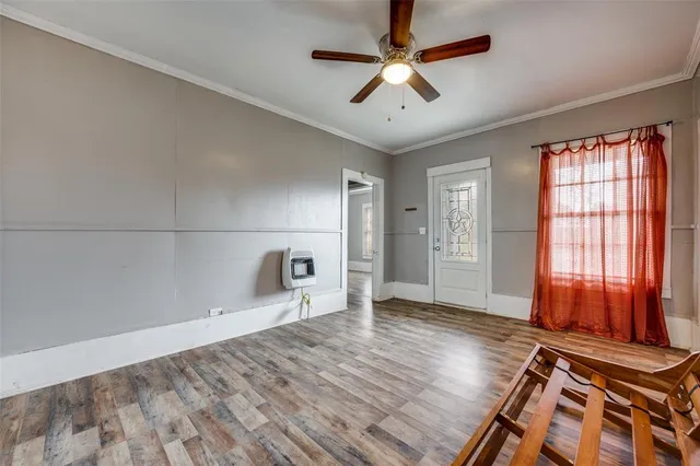 an empty room with wooden floor and a ceiling fan