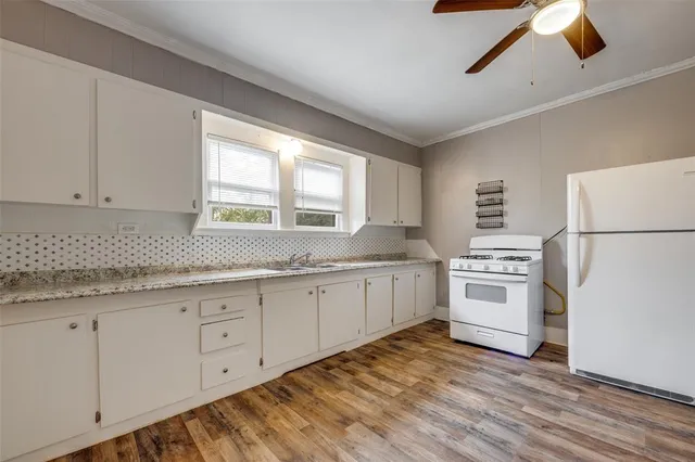 a kitchen with a refrigerator a stove top oven a washer dryer and white cabinets