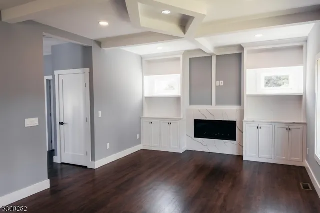 an empty room with wooden floor fireplace and staircase