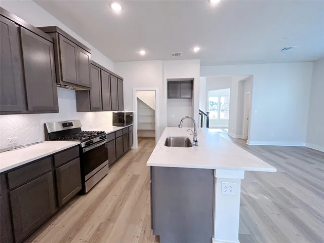 a large kitchen with stainless steel appliances lots of counter space and wooden floor