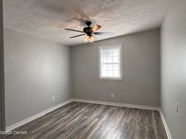an empty room with a window and a ceiling fan