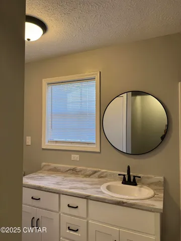 a bathroom with a granite countertop sink and a mirror