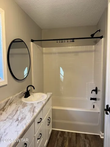a bathroom with a granite countertop sink a mirror and shower