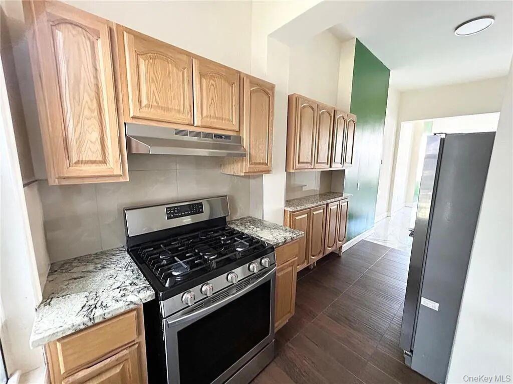 296 Mill Street Poughkeepsie, NY 12601 - Photo 5 of 19 a kitchen with granite countertop a stove and a refrigerator