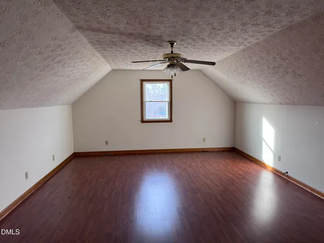 an empty room with wooden floor chandelier and windows