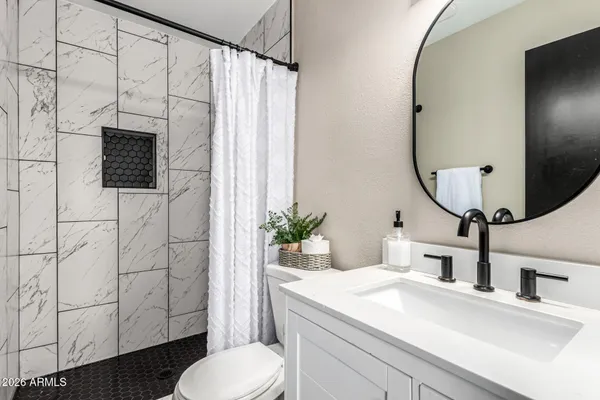 a bathroom with a sink toilet a mirror and shower