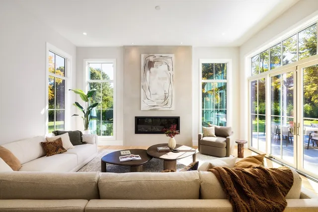 a living room with furniture large windows and wooden floor