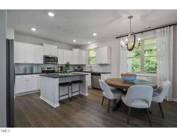 a kitchen with a dining table chairs and white cabinets