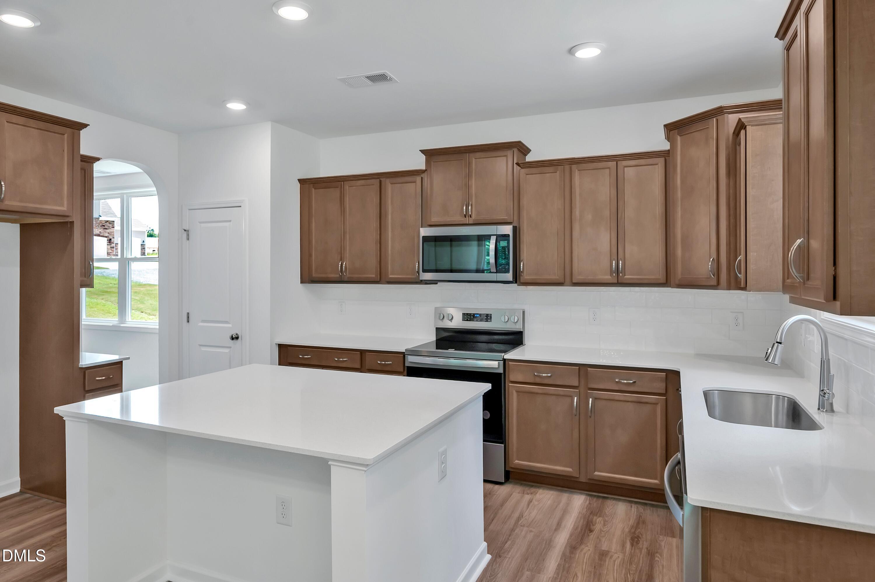 236 White Azalea Way Benson, NC 27504 - Photo 8 of 18 a kitchen with stainless steel appliances a sink a stove a microwave a center island and cabinets