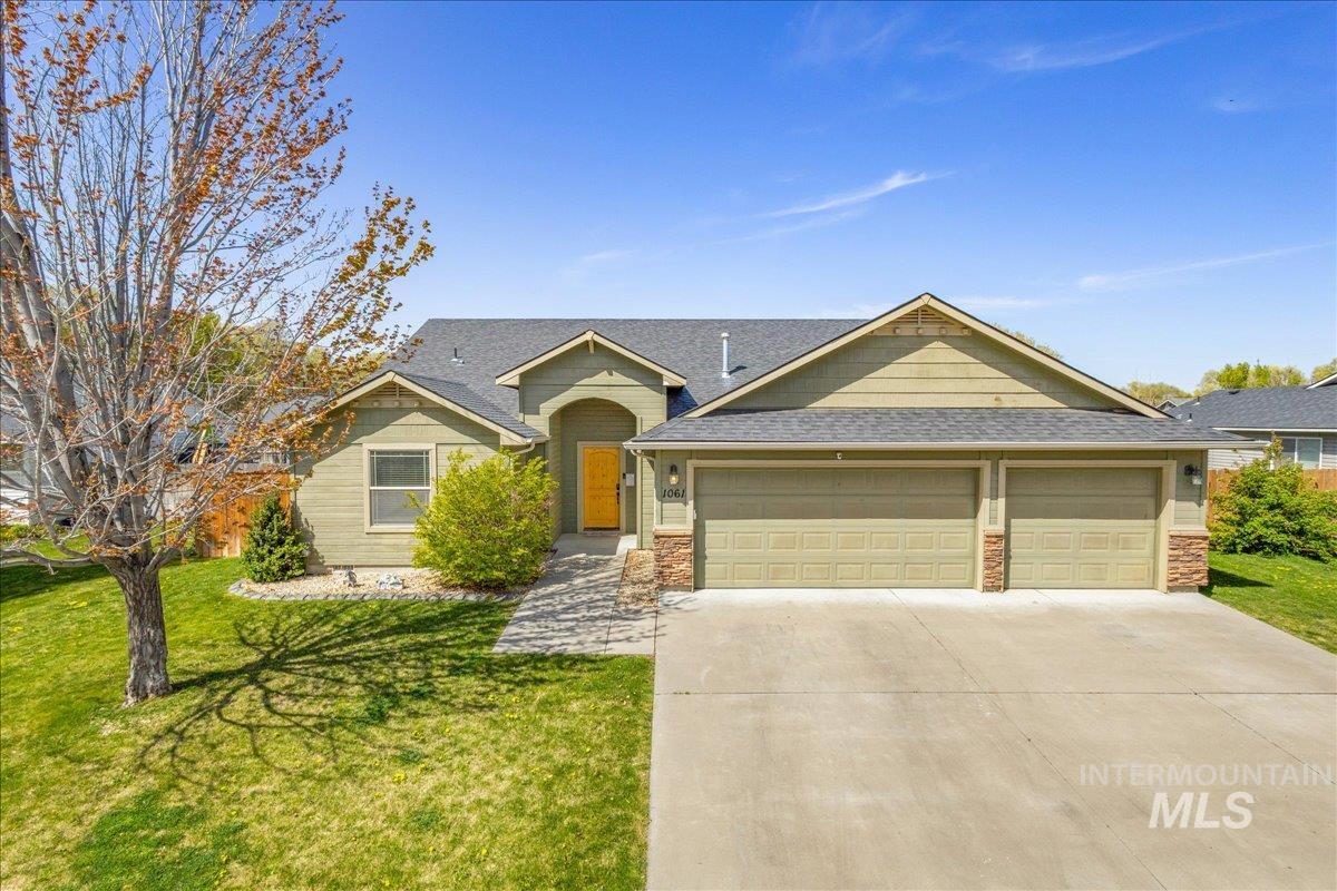 1061 Southwest Independence Mountain Home, ID 83647 - Photo 1 of 1 View of front of house featuring an attached garage, driveway, roof with shingles, a front yard, and stone siding