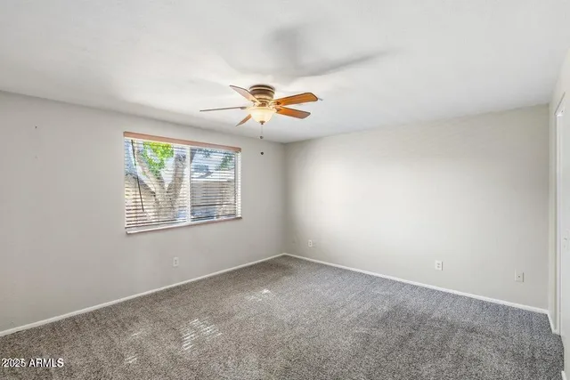 an empty room with a window and a ceiling fan