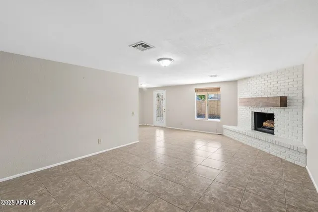 an empty room with windows and fireplace