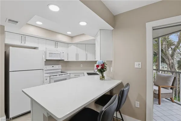 a kitchen with a table chairs refrigerator and cabinets