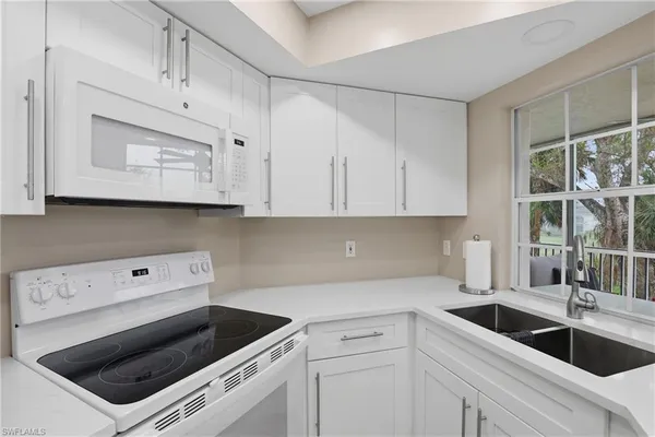 a kitchen with granite countertop white cabinets white stainless steel appliances and a sink