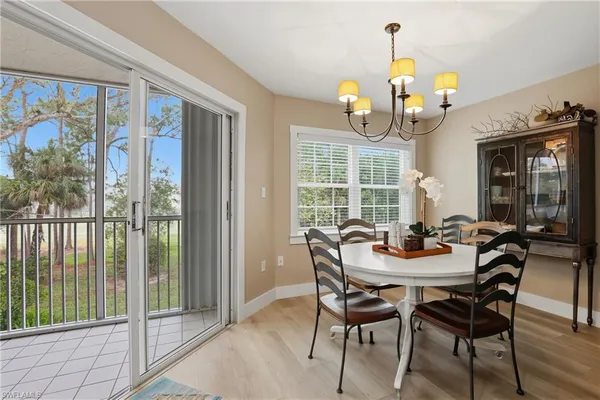 a dining room with wooden floor a chandelier a glass table and chairs
