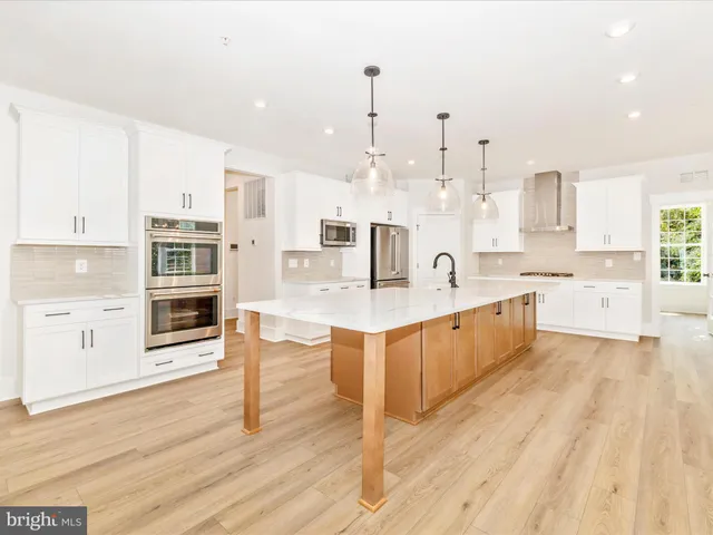a large kitchen with stainless steel appliances kitchen island granite countertop a large counter top a sink dishwasher a dining table and chairs with wooden floor