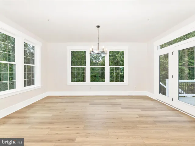 a view of an empty room with wooden floor and windows