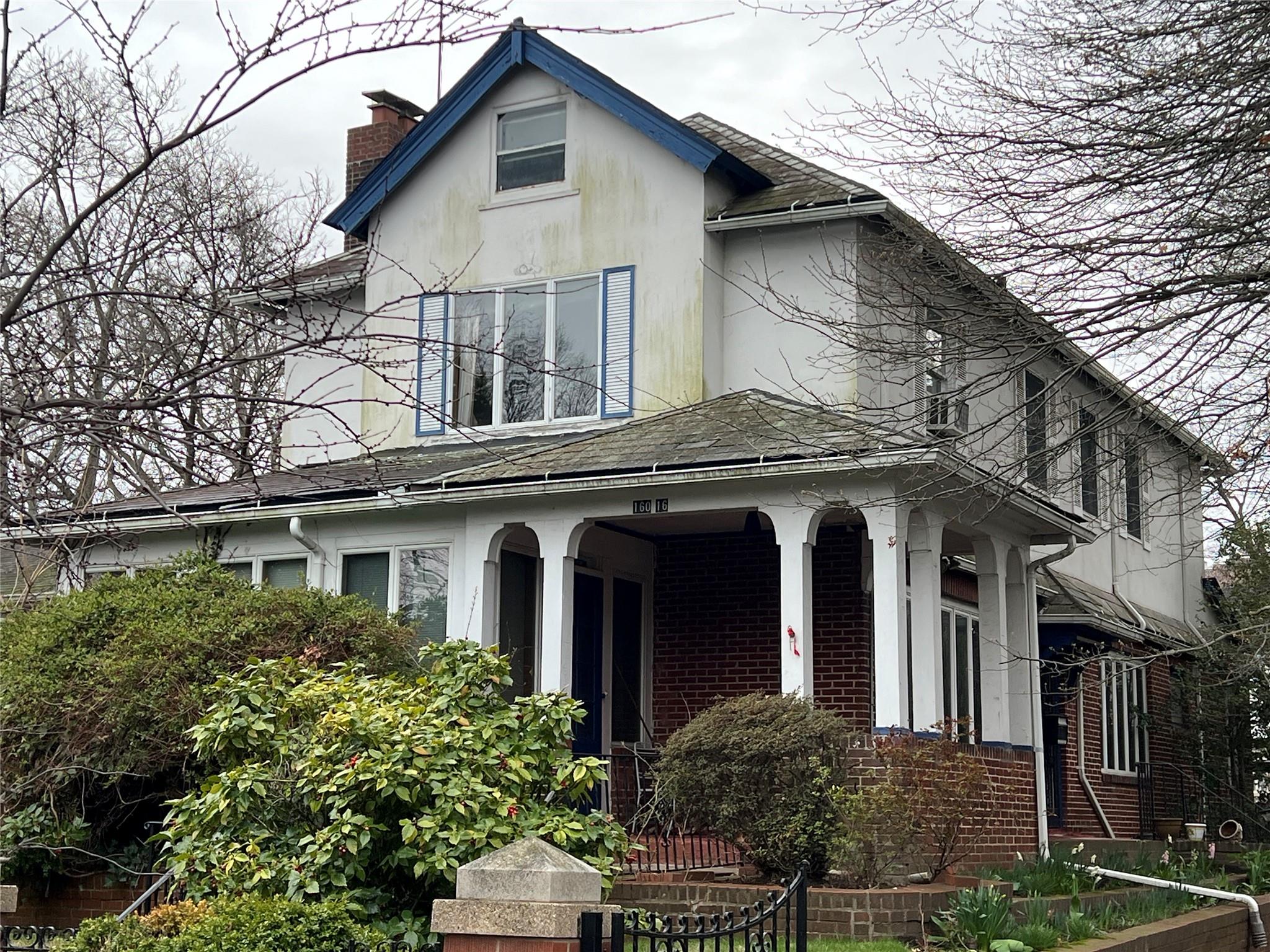 160-16 Riverside Drive Queens, NY 11357 - Photo 2 of 11 a view of a white house with large windows and a small yard