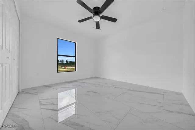 an empty room with a ceiling fan and a window