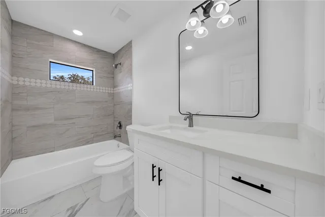 a bathroom with a granite countertop sink a toilet and bathtub