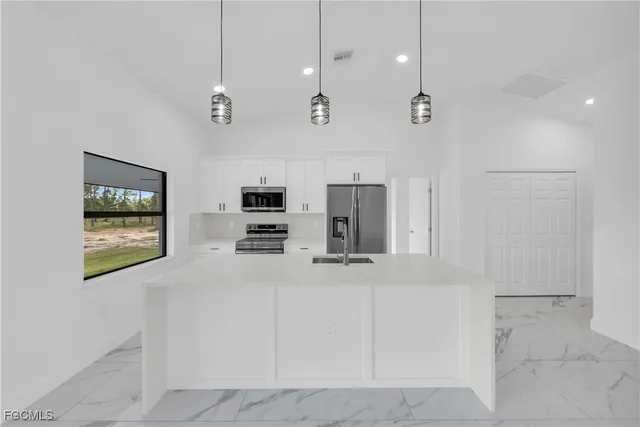 a view of a kitchen with stainless steel appliances kitchen island granite countertop a refrigerator a oven a sink a stove and a refrigerator