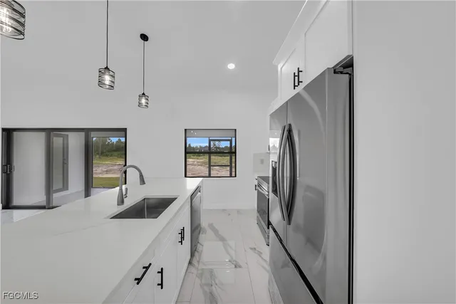 a kitchen with stainless steel appliances a refrigerator a sink a oven and island