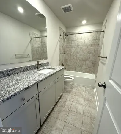 a bathroom with a granite countertop sink a toilet and shower