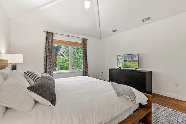 a bedroom with a bed a painting on the wall and a window