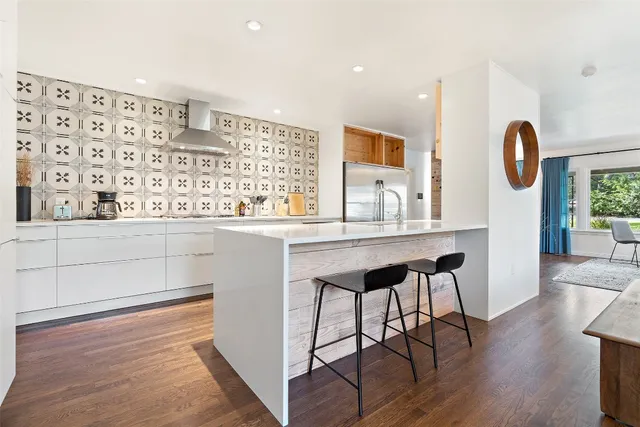 a dining hall with stainless steel appliances granite countertop a stove and a wooden floors